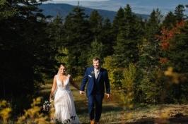 Married couple on wedding day walking in front of colorful trees and mountains